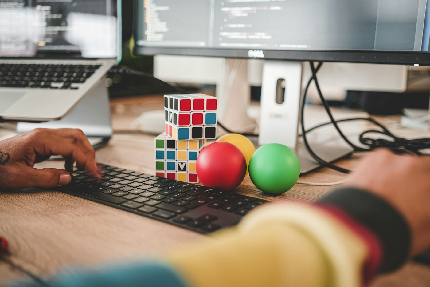 A developer typing at a workstation with code on the monitors